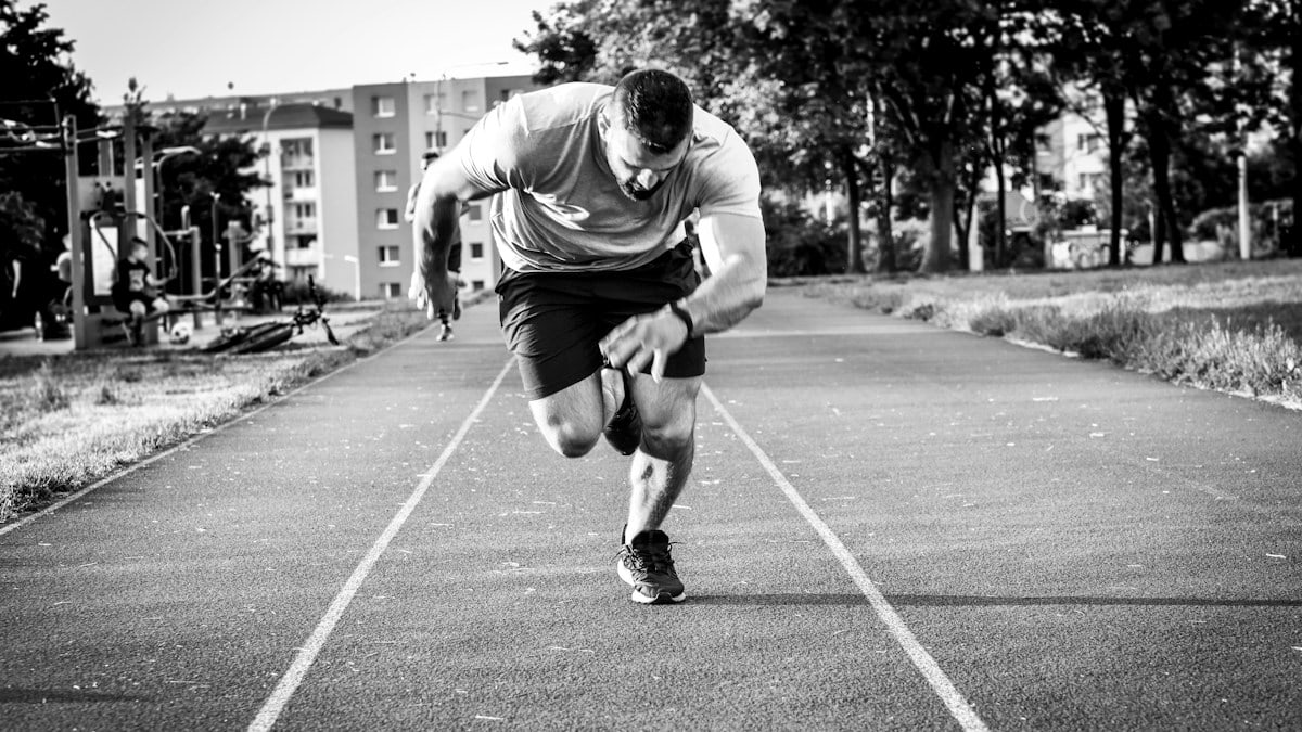 man in gray long sleeve shirt and black shorts running on road during daytime